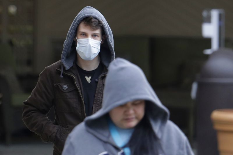 رجل يرتدي قناعًا يمشي بعيدًا عن مدخل مركز رعاية الحياة في كيركلاند ، واشنطن ، بالقرب من سياتل ، الثلاثاء ، 3 مارس ، 2020. وقد تم ربط المرفق بالعديد من الحالات المؤكدة لفيروس كورونا COVID-19. (AP Photo / Ted S. Warren)
