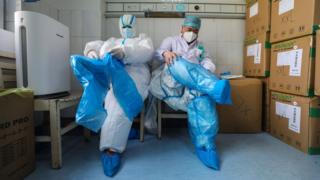 عاملان طبيان يرتديان ملابس واقية في مستشفى لعلاج مرضى فيروس كورونا في ووهان ، الصين.