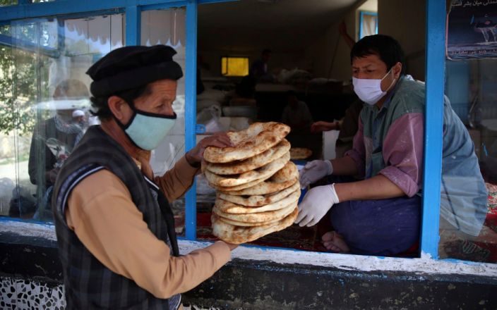 رجل يتسلم خبزًا مجانيًا من البلدية أثناء إغلاق يستهدف الحد من انتشار الفيروس التاجي ، في شهر رمضان المبارك في كابول ، أفغانستان